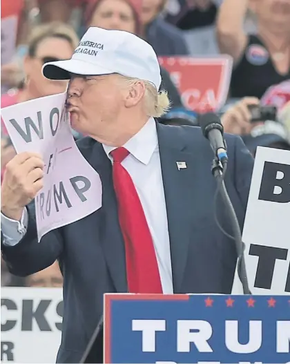  ?? AFP ?? Beso. El magnate republican­o besa un cartel con la leyenda “mujeres con Trump” en un acto en Florida.