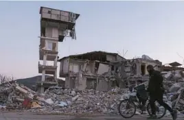  ?? MEHMET KACMAZ/GETTY ?? A man and his son pass what’s left of a building Tuesday in Hatay province in Turkey. A 6.4 magnitude earthquake and dozens of aftershock­s struck Monday.