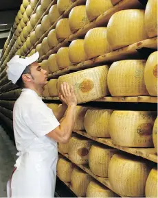  ?? BLOOMBERG ?? A worker selects a whole Parmigiano-Reggiano cheese from a rack ahead of inspection at Coduro cheesemake­rs in Fidenza, Italy.
