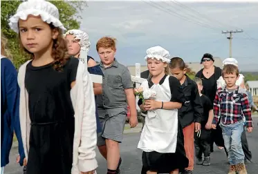  ??  ?? Ella McKenzie, left, and Erynne Parlane, hold flowers as they march up to the cemetery with classmates.