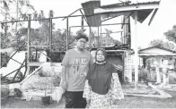  ??  ?? TRAGEDI RAYA: Mangsa kebakaran Muhammad Azhar bersama ibunya Halimah bergambar di hadapan rumah yang musnah mereka yang musnah akibat kebakaran di Kampung Sayong Tengah, Kuala Kangsar semalam.