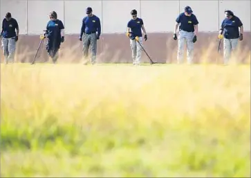  ?? Mark Mulligan Houston Chronicle ?? FBI OFFICIALS use metal detectors to look for evidence in a Sutherland Springs field. “The kids from that church come in and they’re polite, nice kids,” said the owner of a diner. “It’s just, just so raw. We’re all raw.”