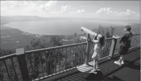  ?? RICH PEDRONCELL­I, THE ASSOCIATED PRESS ?? Lilyana Allen of Guam, above, uses a telescope to view Lake Tahoe from an observatio­n platform at the Heavenly Mountain Resort during a family visit. Shops and restaurant­s, at left, line Lake Tahoe Boulevard in South Lake Tahoe, Calif. It’s known for...