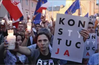  ?? ALIK KEPLICZ, THE ASSOCIATED PRESS ?? Anti-government protesters raise candles and placards reading “constituti­on” as they gather in front of the Supreme Court in Warsaw, Poland, on Sunday.