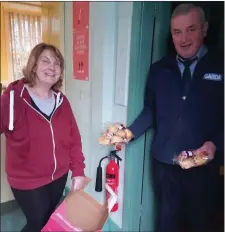  ??  ?? Jo Wallace leaves home baking for self-isolating and cocooning people with Garda Gerry Donovan who delivers them to people outside the village.