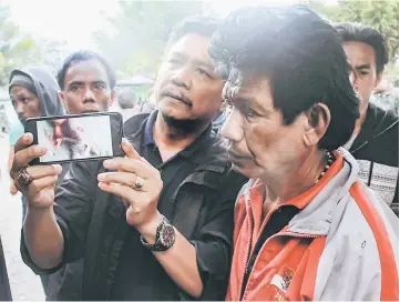  ??  ?? File picture of a man showing a photograph of one of the victims on his smartphone, in Wamena, Papua province.