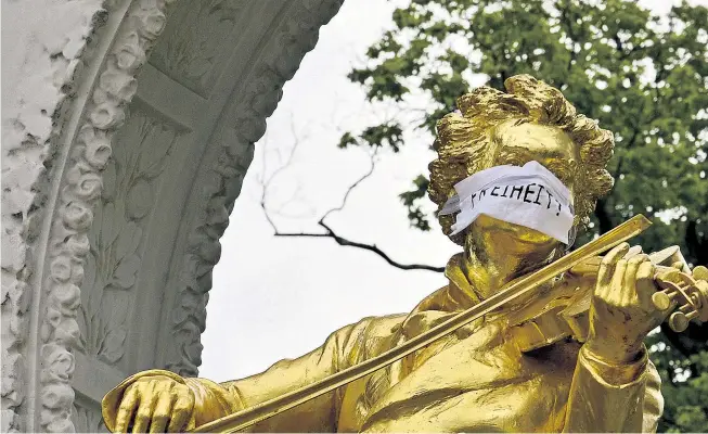  ??  ?? Österreich im Zeichen des Mund-Nasen-Schutzes und seiner Gegner – auch das berühmte Johann-Strauß-Denkmal wurde drapiert.