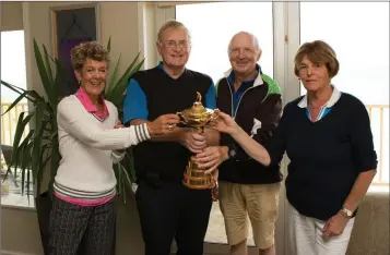  ??  ?? Maureen Feeley, Alistair Smith, Don Deeley, and Eithne Smith get their hands on the Ryder Cup at the 40th Anniversar­y of Founders Day in Blainroe Golf Club.