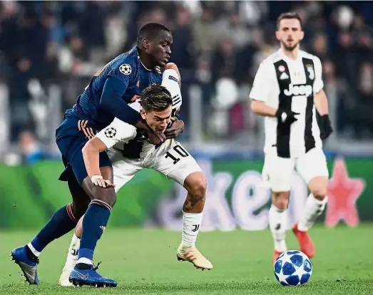  ?? — AFP ?? Getting rough: Juventus forward Paulo Dybala (centre) vying for the ball with Valencia defender Mouctar Diakhaby during the Champions League Group H match at the Juventus Stadium in Turin on Tuesday.