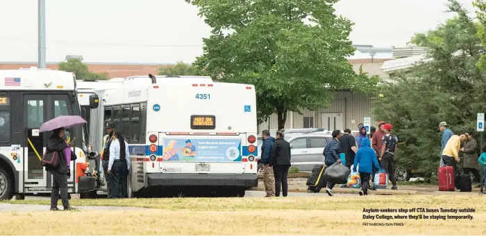  ?? PAT NABONG/SUN-TIMES ?? Asylum-seekers step off CTA buses Tuesday outside Daley College, where they’ll be staying temporaril­y.