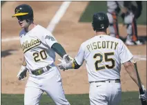  ?? JEFF CHIU — THE ASSOCIATED PRESS ?? The A’s Mark Canha (20) is congratula­ted by Stephen Piscotty after scoring against the Giants in the fourth inning on Saturday in Oakland.