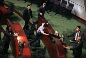  ?? AP/MARK SCHIEFELBE­IN ?? Security officers pursue pro-democracy lawmaker Au Nok-hin as he leaps over desks in the Legislativ­e Council on Thursday to chase Hong Kong Chief Executive Carrie Lam as she leaves a question-and-answer session.