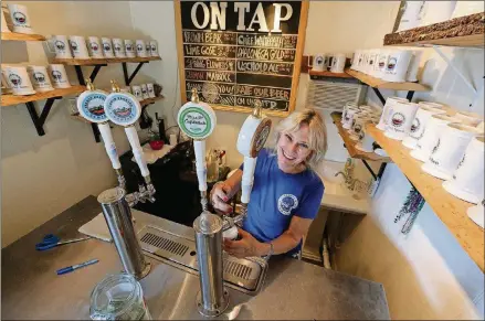  ?? CURTIS COMPTON/CCOMPTON@AJC.COM PHOTOS ?? Tasting room manager Betty Wassmer serves up beer on tap at Fannin Brewing in Blue Ridge.