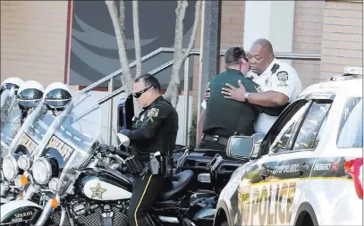  ?? Red Huber ?? The Associated Press Law enforcemen­t agents embrace outside Orlando Regional Medical Center on Monday after a shooting that severely injured an Orlando police officer responding to a domestic dispute call Monday.