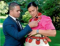  ?? PHOTO: PHOTOSPORT ?? Dame Valerie Adams’ husband Gabriel Price makes a final adjustment before her investitur­e ceremony in Auckland last week.