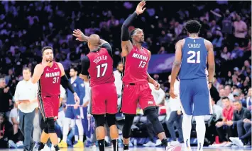  ?? MATT SLOCUM AP ?? Max Strus, left, P.J. Tucker and Bam Adebayo high-five each other while Joseph Embiid walks by during Miami’s victory over Philadelph­ia in Game 6. Miami will play Boston or Milwaukee in the next round.