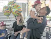  ?? REBECCA BLACKWELL — THE ASSOCIATED PRESS ?? Capt. Eric Hernandez lifts up his daughter Isabella, 3, as his wife, Yaimara, and son Eric, 4, look on, as members of Miami-Dade Fire Rescue’s urban search and rescue team are reunited with their families on Friday.