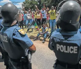  ?? /AFP ?? Thin line: Police officers stand guard as ANC and EFF supporters protest against the language and admission policies at Hoërskool Overvaal in Vereenigin­g. The school has been at the centre of racial tension after it refused to accept 55...