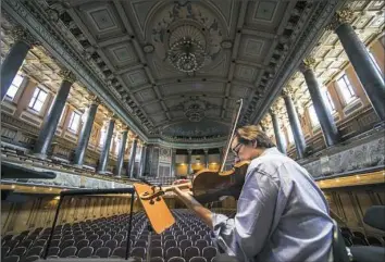  ?? © Todd Rosenberg Photograph­y ?? Pittsburgh Symphony Orchestra associate concertmas­ter Mark Huggins finds a quiet moment to warm up onstage before the rehearsal in Wiesbaden, Germany.