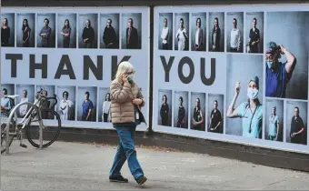  ?? WILLIAM WEST / AFP ?? A woman walks past a tribute to healthcare workers outside a hospital in Melbourne on Tuesday, when the hard-hit Victoria state recorded just one more COVID-19 case.