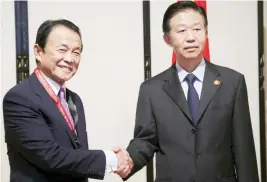  ??  ?? Chinese Finance Minister Xiao Jie, right, shakes hands with his Japanese counterpar­t Taro Aso during their bilateral meeting in Yokohama, Japan on Saturday. (Reuters)