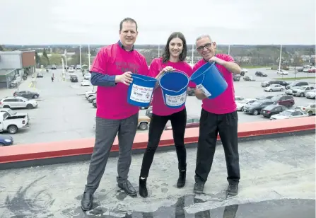  ?? JESSICA NYZNIK/EXAMINER ?? Derek Deyell, manager of The Brick, left, Emily Ferguson, Habitat For Humanity Peterborou­gh and Kawartha resource developmen­t manager, and Paul Rellinger hold up empty buckets atop The Brick's rooftop on Wednesday. They hope to fill those buckets with...