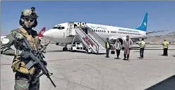  ?? AP ?? A Taliban soldier stands guard as passengers disembark at Kabul airport on Sunday.