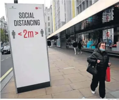  ?? NEIL HALL / EFE ?? Una mujer camina por una inusualmen­te tranquila zona comercial de Oxford Street, ayer en Londres.