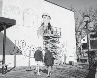  ?? Jon Shapley / Staff photograph­er ?? Bob Pando, left, and his wife, Trilla, get a look at Gonzo247 as he works on a mural at the University of St. Thomas on Wednesday. “A mural,” Trilla Pando exclaimed. “We love murals.”