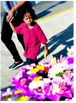  ??  ?? Four-year-old Giomar Baxter looks at the wreaths laid yesterday as he walked with his mother, Maresha Baxter.