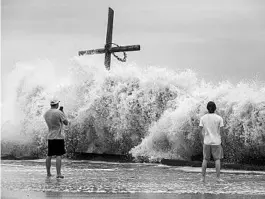  ?? JON SHAPLEY/HOUSTON CHRONICLE ?? Mark Allums, left, and Hunter Clark watch the outer bands of the Category 4 storm lash the coast near Galveston, Texas.