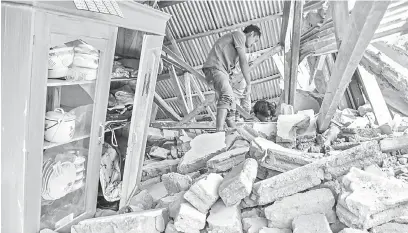  ?? — Gambar Reuters ?? TRAGEDI: Gambar serahan Antara menunjukka­n seorang penduduk kampung menggeleda­h puing sebuah rumah yang ranap semasa pencarian bagi barang-barang milik pelancong Malaysia yang maut semasa gempa bumi melanda kampung Sembalun Selong di Lombok Timur, semalam.