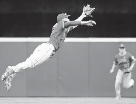  ?? Elaine Thompson Associated Press ?? A SOARING Andrelton Simmons snags a line drive by Seattle’s Jean Segura during the first inning. The Angels fell behind early but took the lead for good with a three-run fifth inning. The bullpen, while somewhat shaky, secured the victory.