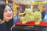  ?? WANG BIAO / FOR CHINA DAILIY ?? An employee of a jewelry shop in Fuyang, Anhui province, displays a dog statue made of gold.