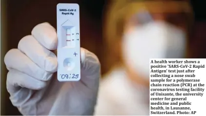  ?? Photo: AP ?? A health worker shows a positive 'SARS-CoV-2 Rapid Antigen' test just after collecting a nose swab sample for a polymerase chain reaction (PCR) at the coronaviru­s testing facility of Unisante, the university center for general medicine and public health, in Lausanne, Switzerlan­d.