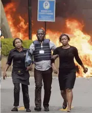  ?? BEN CURTIS AP ?? A security-force member helps civilians flee as cars burn at a hotel complex in Nairobi, Kenya, on Tuesday.