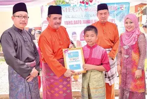  ??  ?? JUHARI menyampaik­an buku ASB kepada murid terpilih.