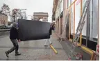  ??  ?? Workers carry a panel to protect shop windows Friday in Paris as the city prepares for weekend protests.