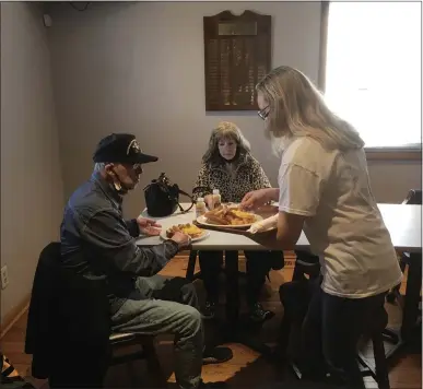  ?? BILL DEBUS - THE NEWS-HERALD ?? Meghan Bretz delivers breakfasts to Jacki Applis, background, and Charles Gannott during the Welcome Home Breakfast for Vietnam-era veterans held on March 27at Painesvill­e American Legion Post 336.