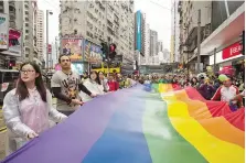  ?? — AFP photo ?? This file photo taken on November 26, 2016 shows participan­ts of Hong Kong’s annual pride parade walk through the streets with a large rainbow flag.