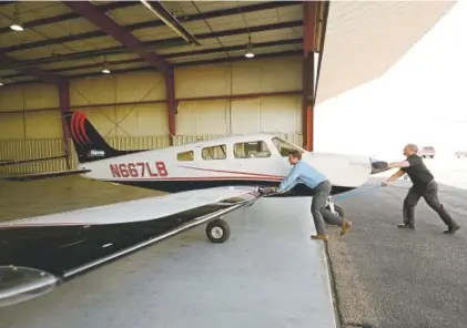  ??  ?? Woodridge and Lawrence move a training aircraft at the Greeley-weld County Airport on Thursday.