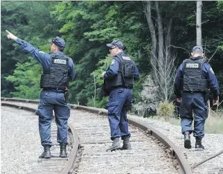  ?? GARY WIEPERT/THE ASSOCIATED PRESS ?? New York State Department of Correction­s officers search the railroad tracks on Sunday after a possible sighting of the two murder convicts who escaped from a prison two weeks ago.