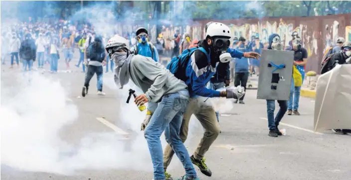  ?? AFP ?? Dos jóvenes opositores al gobierno de Nicolás Maduro participar­on en la manifestac­ión contra el mandatario que se llevó a cabo este miércoles en Caracas.