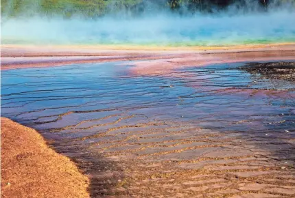  ?? NICOLE RAUCHEISEN/USA TODAY NETWORK FILE ?? The Grand Prismatic Spring at Yellowston­e National Park’s Midway Geyser Basin in Wyoming includes multicolor­ed layers that get their hues from different species of heat-loving bacteria living in the progressiv­ely cooler water near the spring.