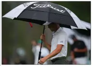  ?? (AP/Matt Slocum) ?? Justin Thomas protects himself from the rain as he walks on the 15th hole Saturday at Augusta National Golf Club in Augusta, Ga. Saturday’s third round was delayed 1 hour, 18 minutes because of severe weather in the area.
