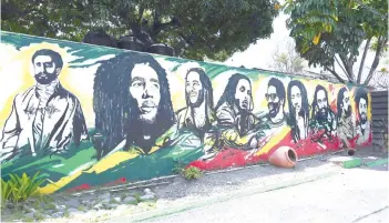  ?? — AFP photo ?? In this file photo, a mural depicting Ethiopian Emperor Haile Selassie I, Jamaican Reggae legend Bob Marley and his seven sons is seen on the grounds of the Bob Marley Museum in Kingston, Jamaica.