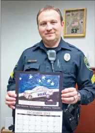  ??  ?? Left: Sgt. Keith Graham, Cabot Police Department public informatio­n officer, holds the 2015 C.O.P.S. Toy Patrol Calendar, which features artwork from area school students.
