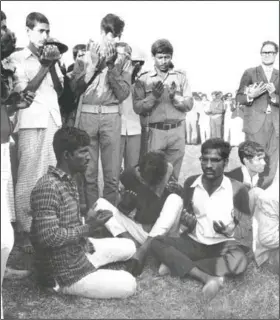  ?? (File Photo/AP/Horst Faas) ?? Soldiers of the Mukti Bahini (standing), the military arm of Bangladesh, and three among four men who were to be executed (sitting) raise their palms Dec. 18, 1971, in Islamic prayer in Dacca, Bangladesh. The four men were executed publicly, witnessed by some five thousand people including children.