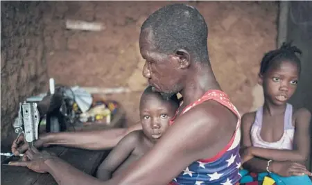  ??  ?? Marie Kamara’s stepfather, Osman, works on his sewing machine last month in Komao, Sierra Leone. Marie became a child bride for $50 inside a bowl along with the traditiona­l kola nut. At right is one of Marie’s four sisters.