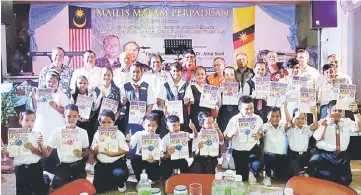  ??  ?? Dr Jerip (fourth left, back row) posing with the school children holding their UPSR model papers.